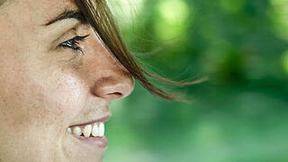 Frau im Profil lächelt vor grünem Hintergrund