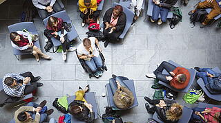 Gruppe an Personen die auf Stühlen sitzt, in der Mitte ein Rollstuhlfahrer