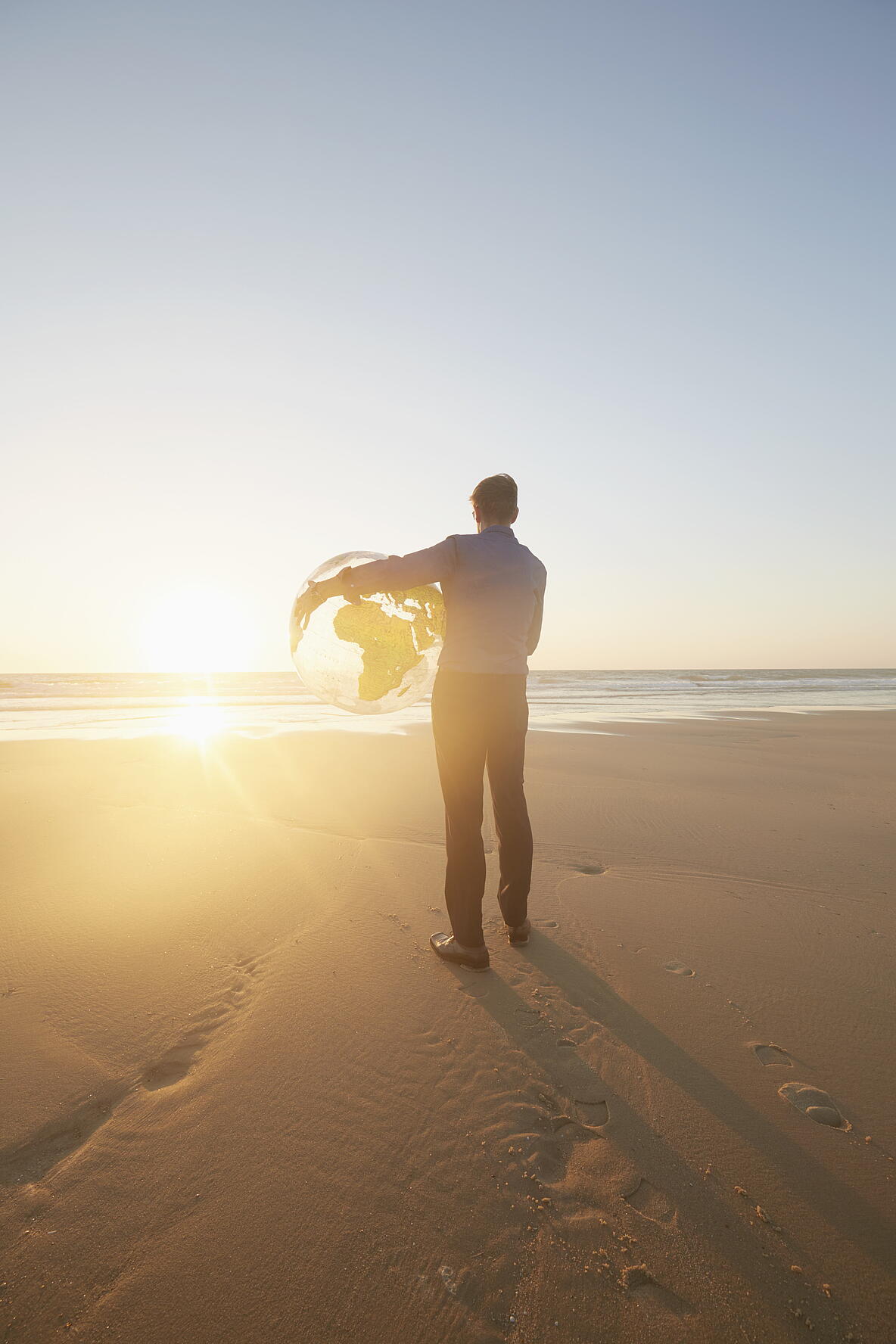 Mann der einen Globus am Meer hält