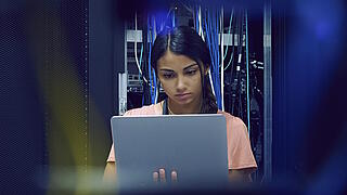 Frau mit Laptop im Serverraum