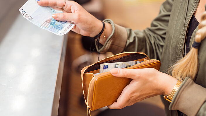 Ausschnitt einer Hand die mit Euroscheinen bezahlt