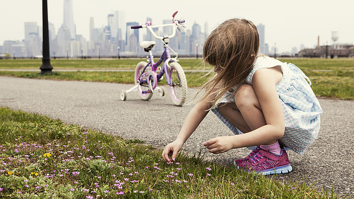 Kind, das am Wegrand hält um Blumen zu pflücken