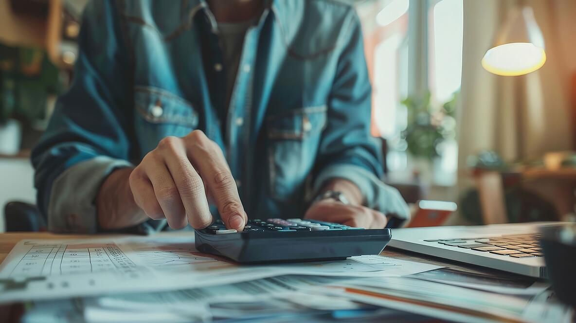 Mensch tippt auf einem Taschenrechner