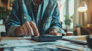 Mensch tippt auf einem Taschenrechner